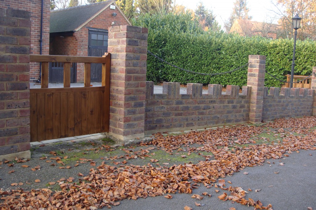 Brick boundary wall with piers and a timber gate on a residential street