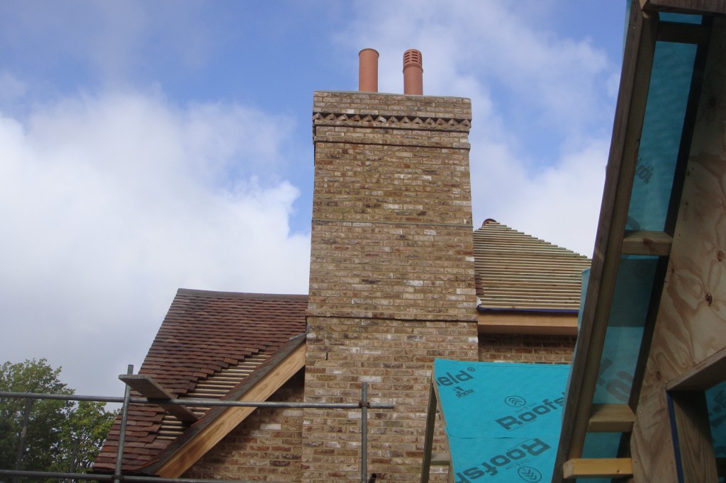 New brick chimney stack on a roof under construction